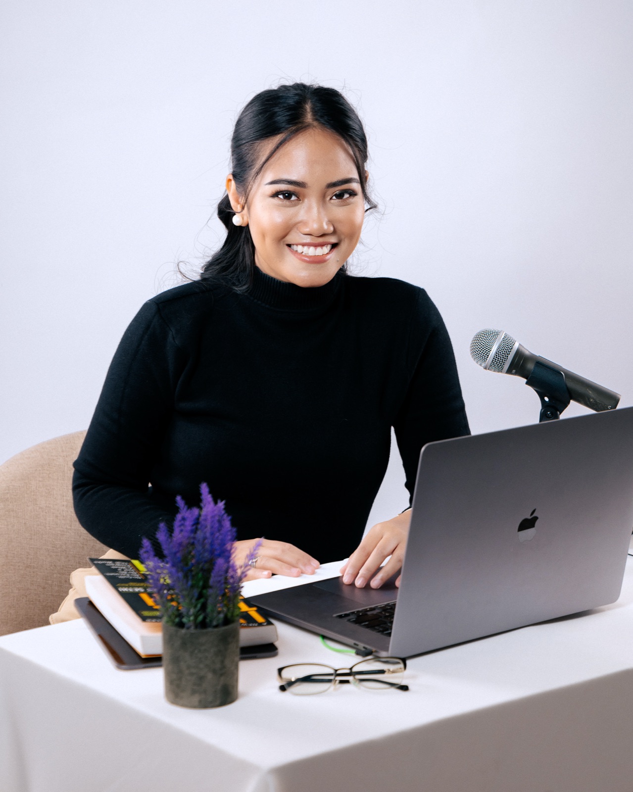 Demi Bernice smiling at her desk with a laptop and microphone